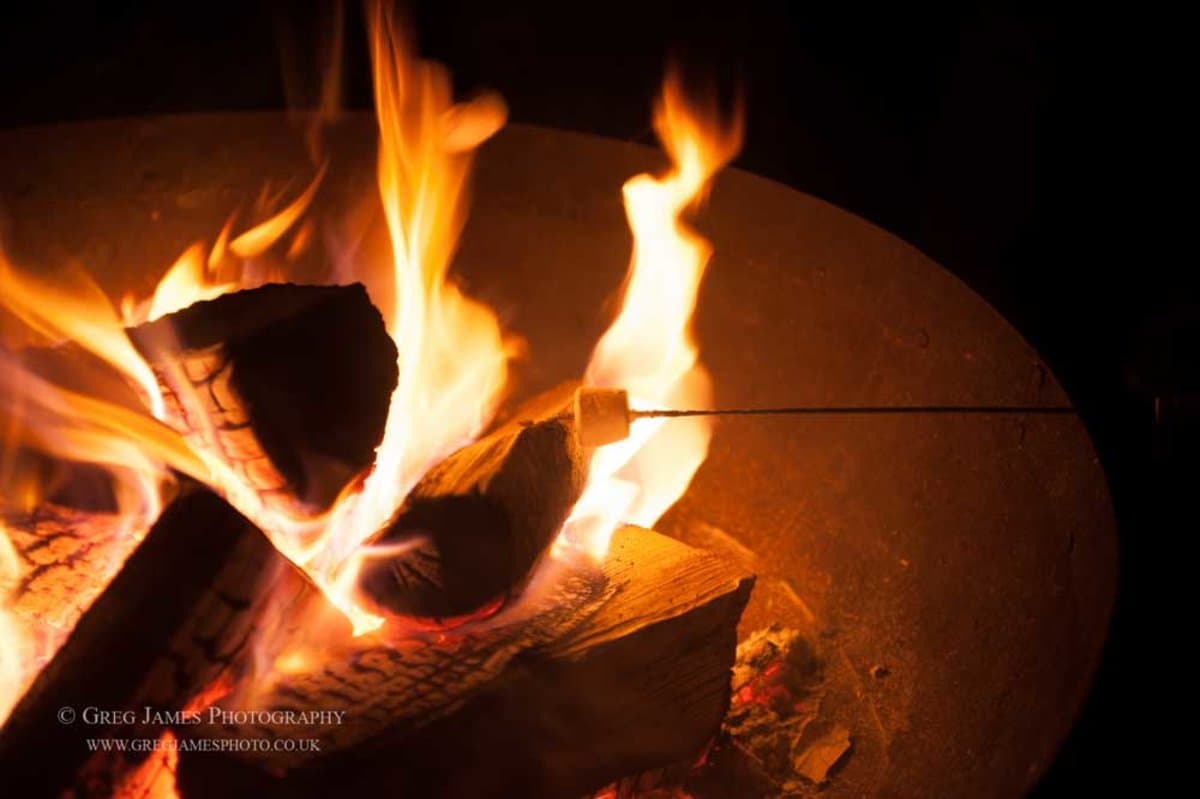 Wedding fire pit with flames and marshmallow on a skewer — cosy evening atmosphere