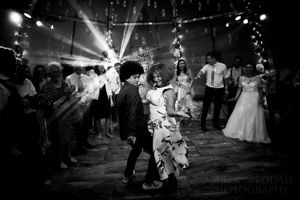 Packed wedding dancefloor in a tipi with fairy lights, moving heads and guests celebrating — Martin Beddall Photography