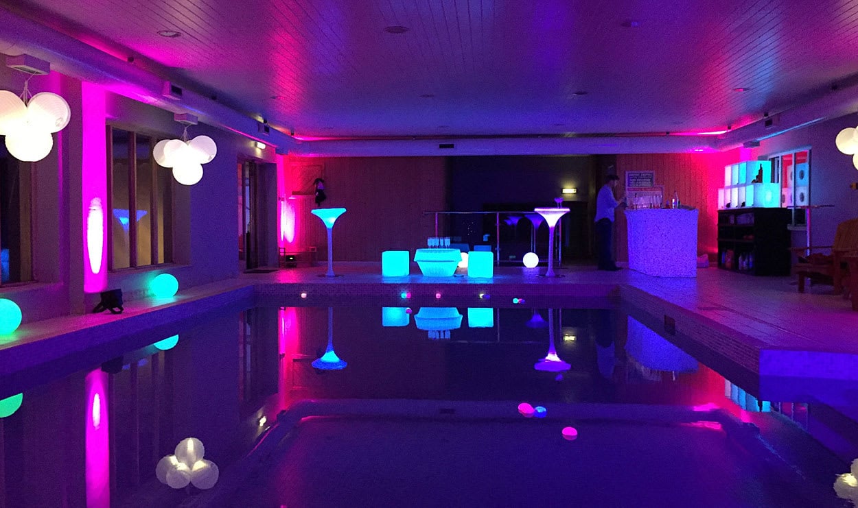Pool party with colourful lighting reflecting on the water – stylish summer celebration