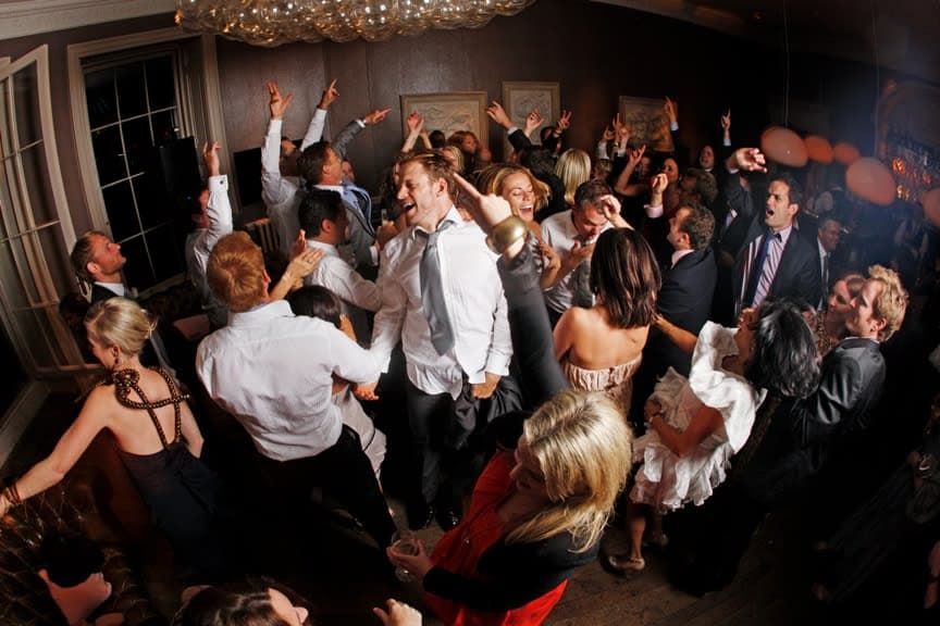 Packed wedding dancefloor with guests dancing at a formal reception