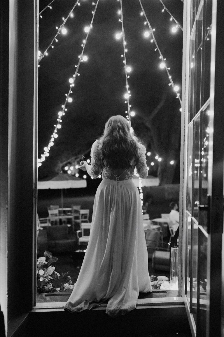 A bride standing on a step with wedding lighting fanning out from above.
