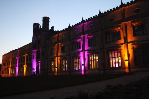 Ashton Court Mansion in Bristol with exterior LED lighting in amber and pink at dusk.