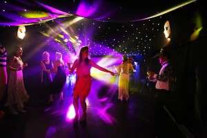 A 21st birthday party in a marquee with coloured disco lights and people smartly dressed.