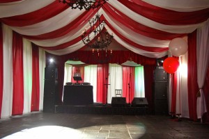 A circus themed party with big top, stage and dj decks ready for people to arrive. Red and White stripped Big Top style.