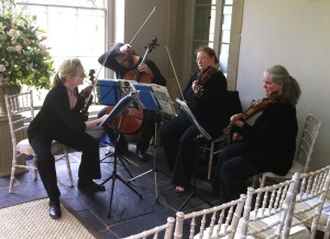 A string quartet rehearsing for a wedding with empty chairs in the foreground.