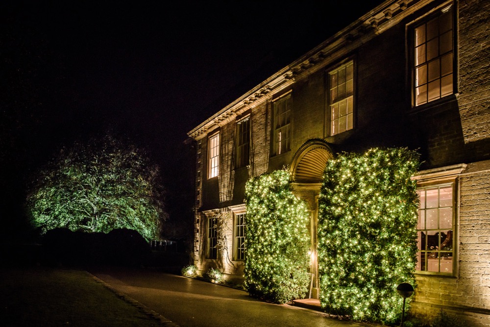 Front of Babington House with bush lighting. Nightime with an oak tree in hte background light up