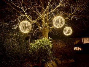 3 spheres made from led lights suspended from a tree in the winter