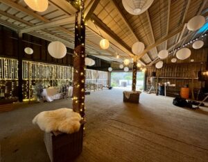 Barn transformation, daytime, lots of white shades hanging from the ceiling with stables to the left.