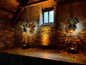 Stunning lighting reflections from a cluster of glitter balls illuminating both sides of a stage, creating a dazzling and atmospheric effect.